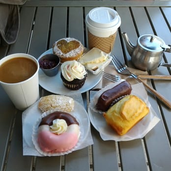 table with coffee, donuts, cupcakes, and other pastries on top
