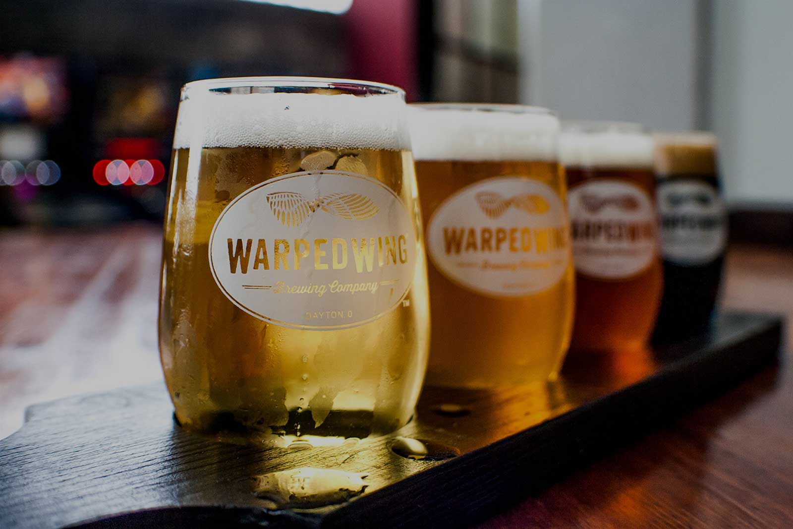 Different kinds of beer lined up on a bar