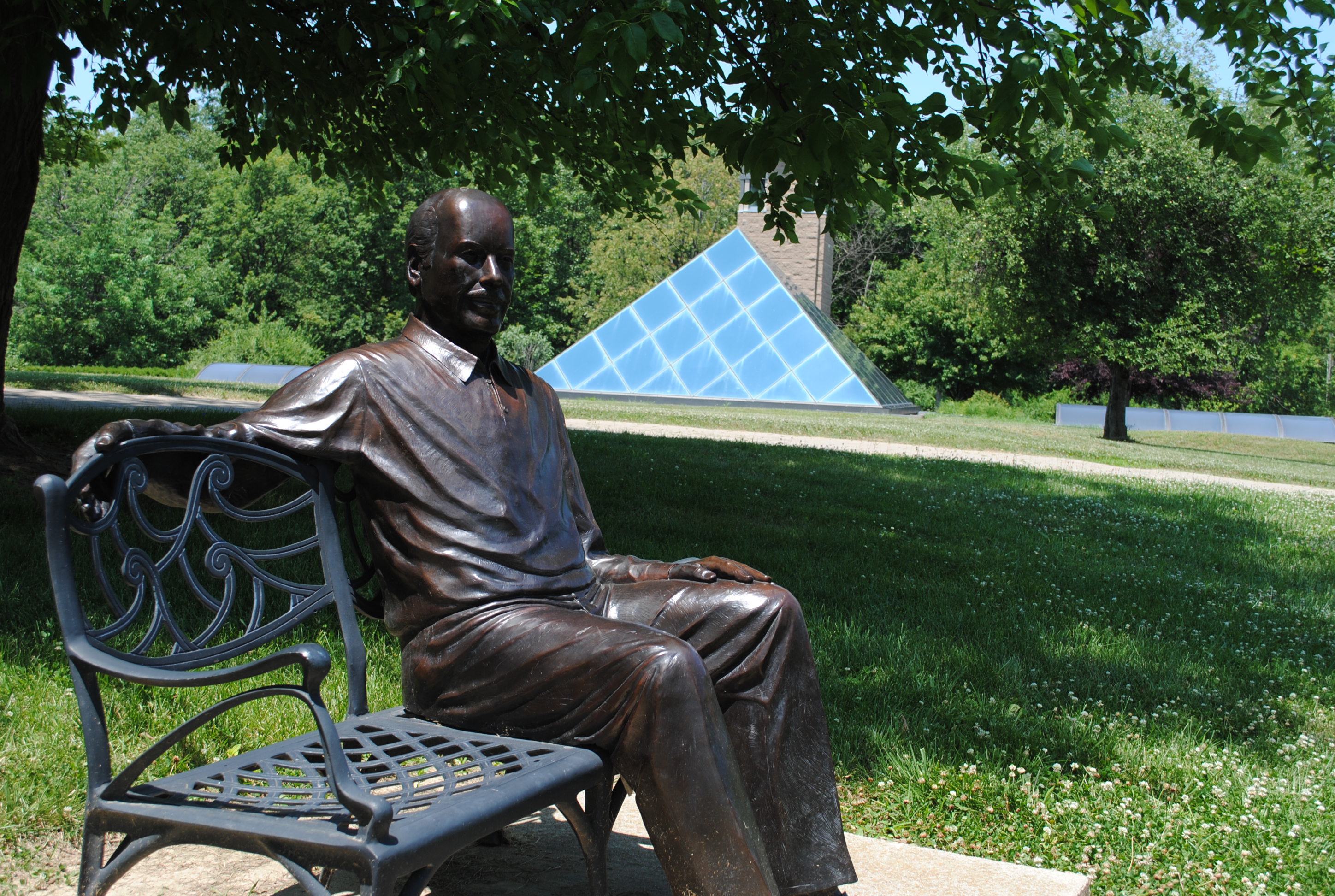 Statue of man on a bench with Pyramid House in the background