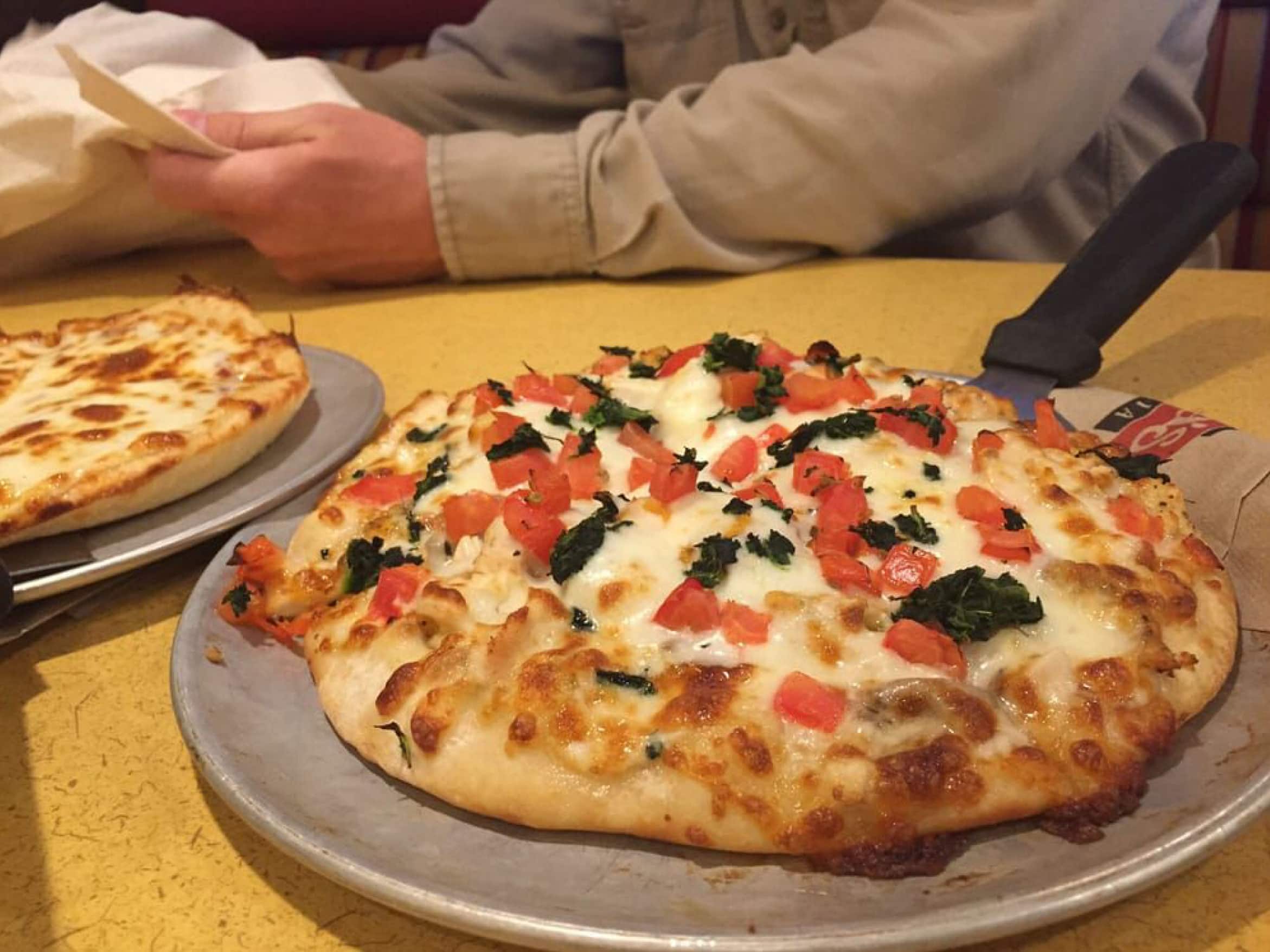 Best pizza is fresh pizza! Man reads recipt with 2 pies on the table.