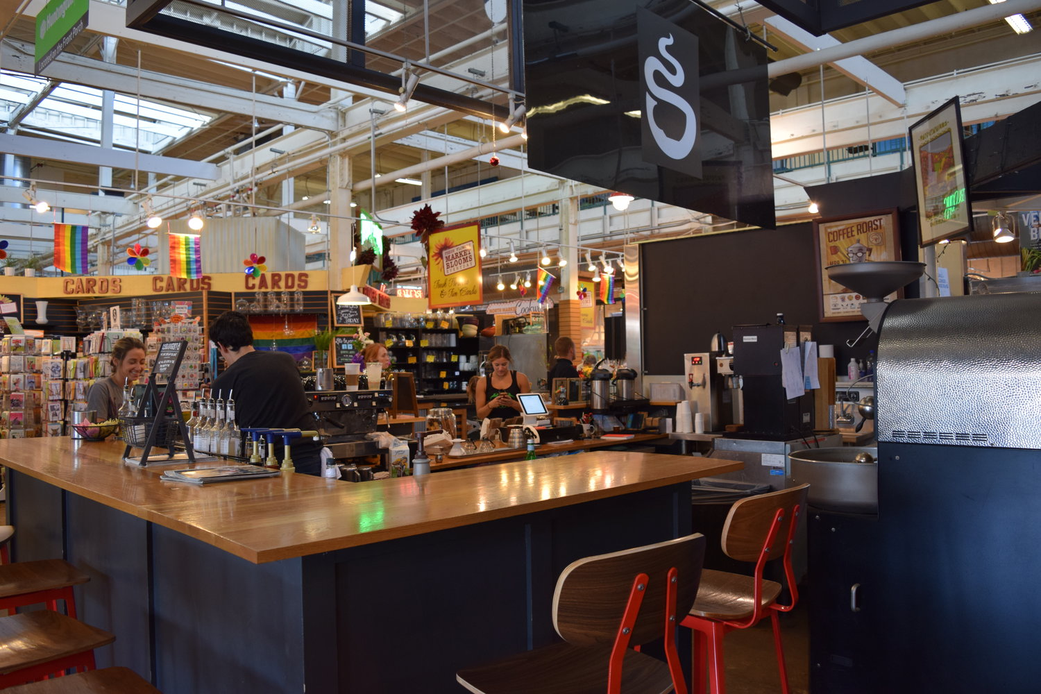 Bar-style kiosk with barista serving a customer, all inside a large public market