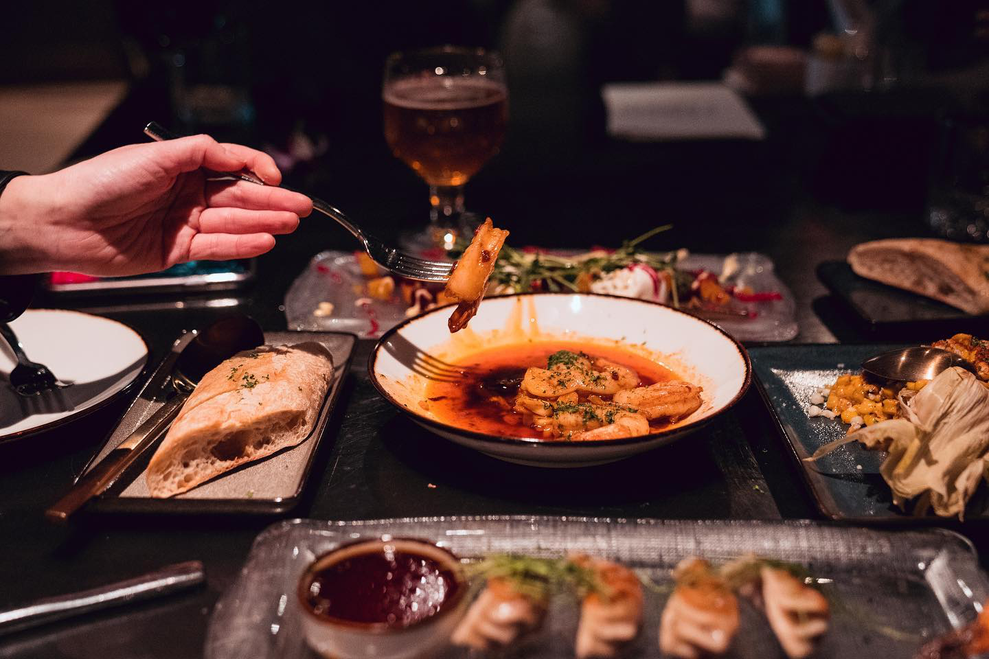 Hand picking up shrimp from dish in center of fully set table at Fireproof