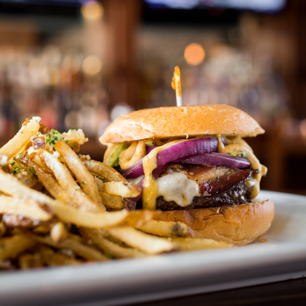 Burger with cheese and bacon alongside heaping pile of fries