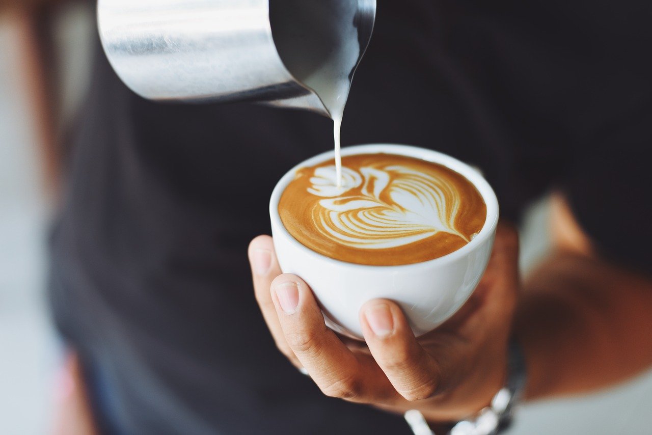 a barista pours cream into a latte
