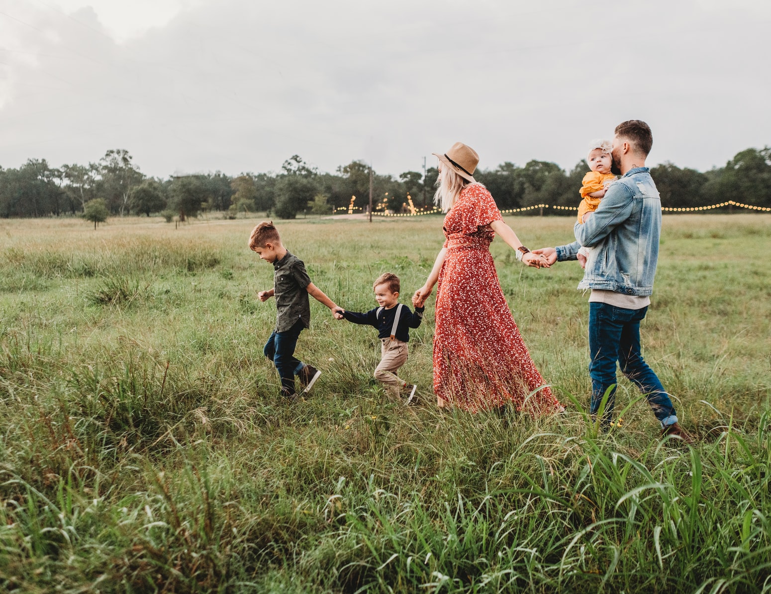 family holding hands and walking in a grassy field