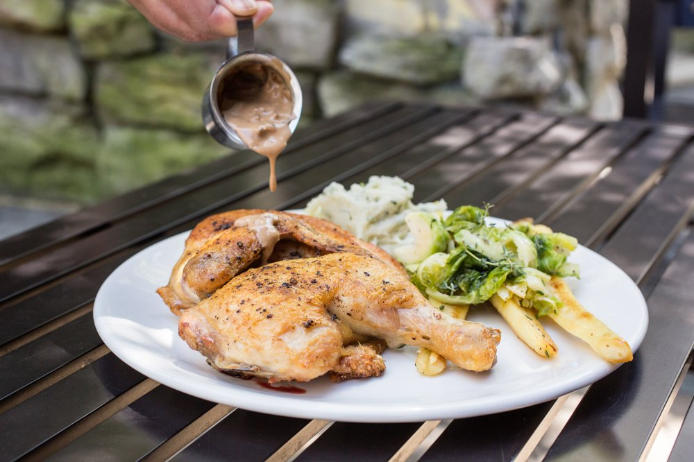 A Gorgeous Plate of Grilled Chicken Thighs Glistening in Brown Gravy With A Side Of Potatoes And A Ceaser Salad
