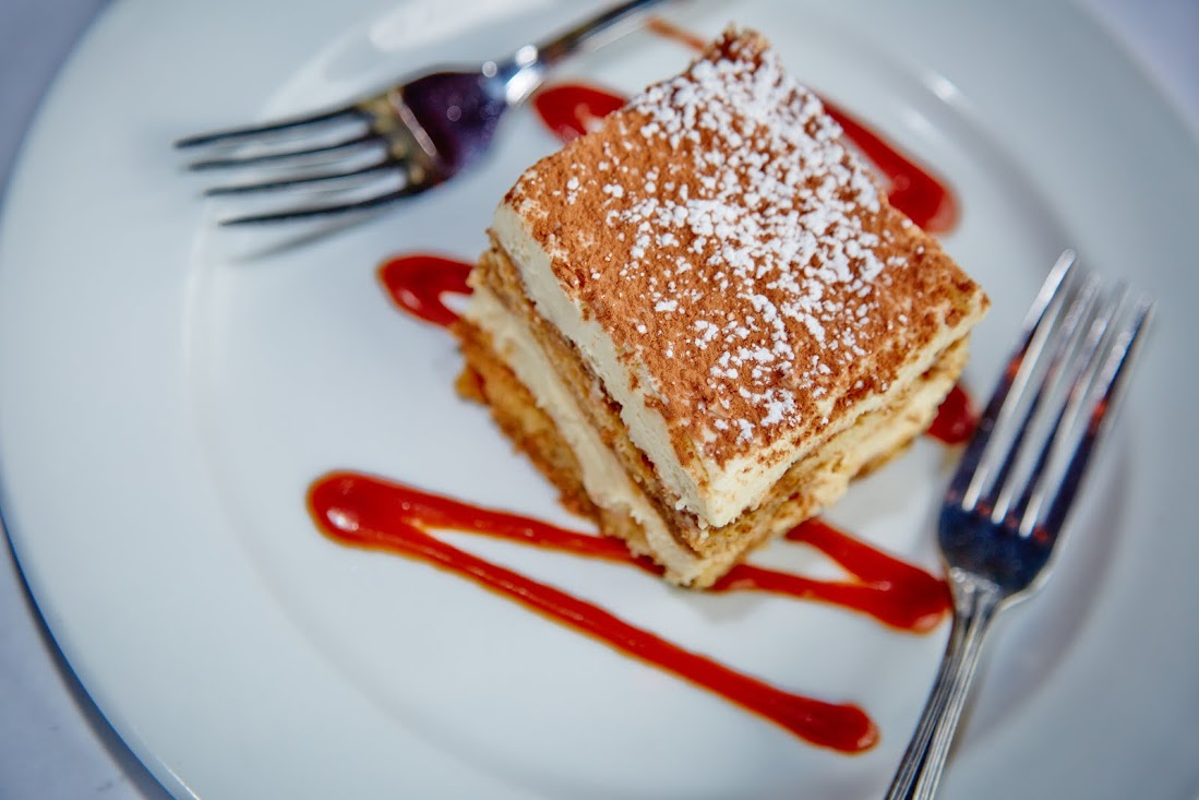A Slice Of Tiramisu Resting On Top Of A Drizzle Of Strawberry Sauce