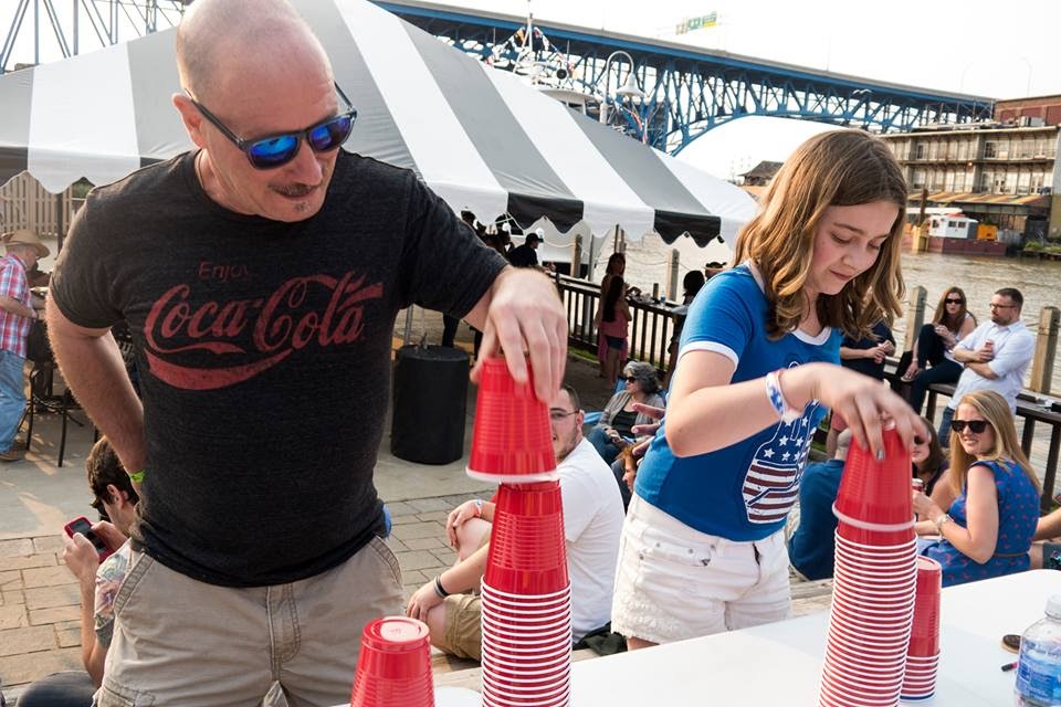 man and young girl stacking red plastic cups in front of tent