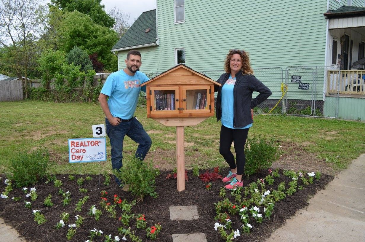 man and woman standing by a Little Free Library in a yard