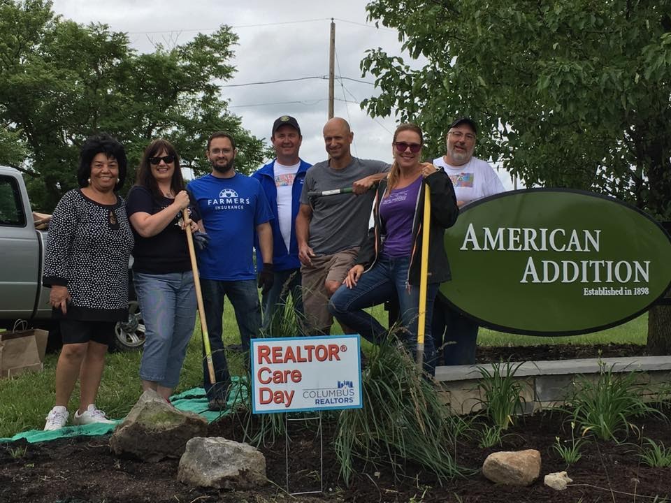group of people with shovels standing next to Realtor Care Day sign