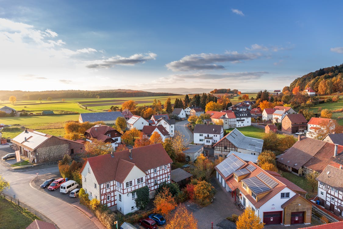 An aerial view of a small neighborhood with fields and trees in the background.
