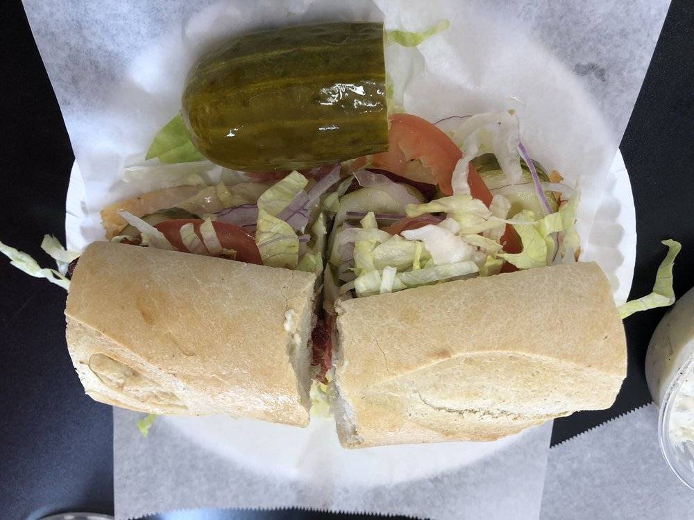A sandwich with a pickle on the side from Richie's New York Corner Deli