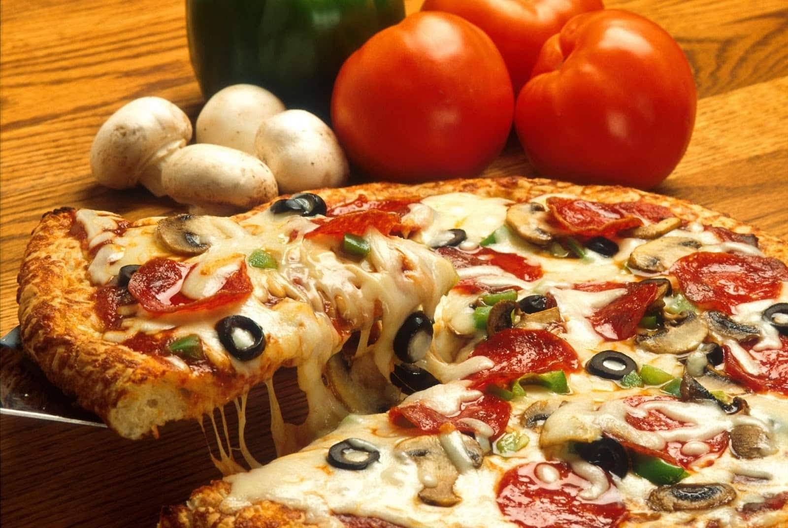 pizza with pepperoni, olives & mushrooms on wood table at Jac N Do's