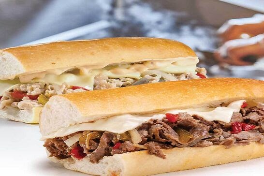 Two sub sandwiches topped with melted cheese.