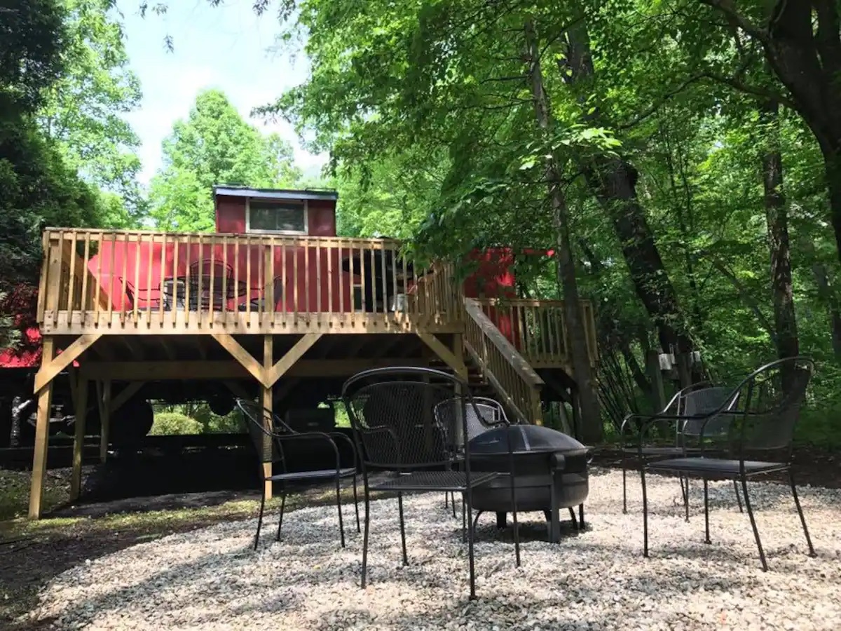 Wooden deck attached to the back of the Caboose with a lower seating area and fire pit