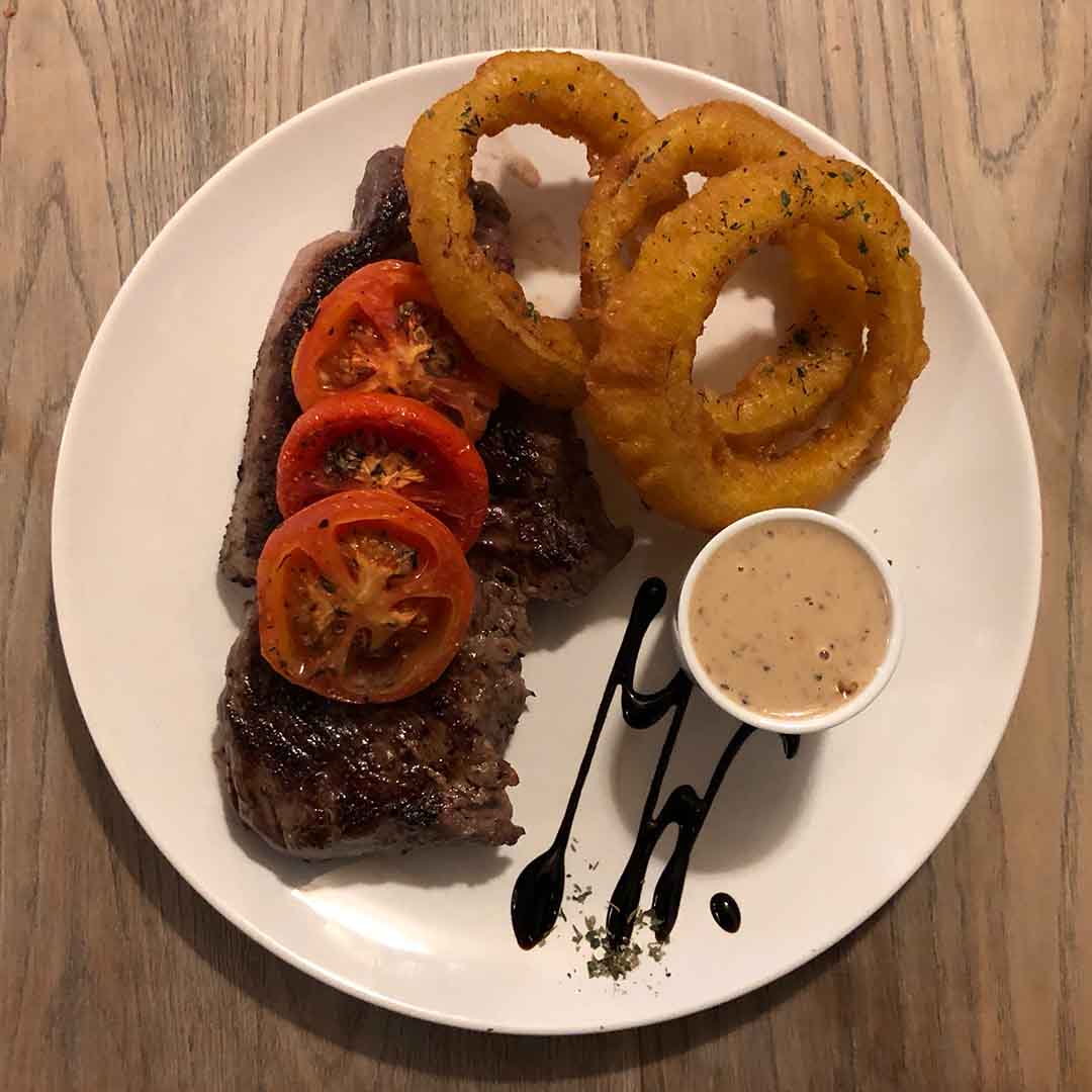 Falcon Steakhouse 14oz Sirloin steak with tomatoes, onions rings and peppercorn sauce