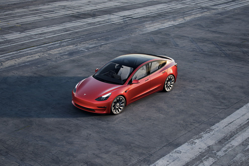 Tesla Model 3 zachycený na rozlehlém parkovišti, kde kromě tohoto auta nejsou jiné vozy.