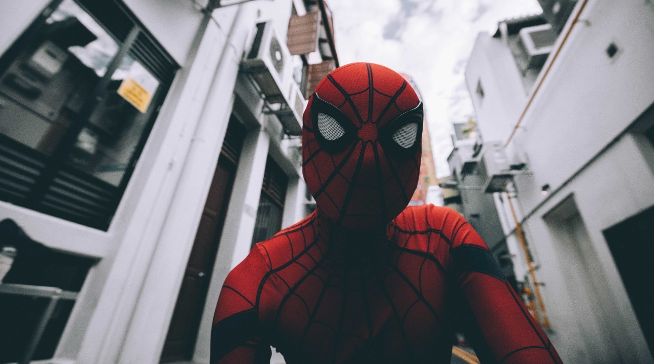 Foto do rosto com máscara do super herói Homem Aranha e prédios de fundo