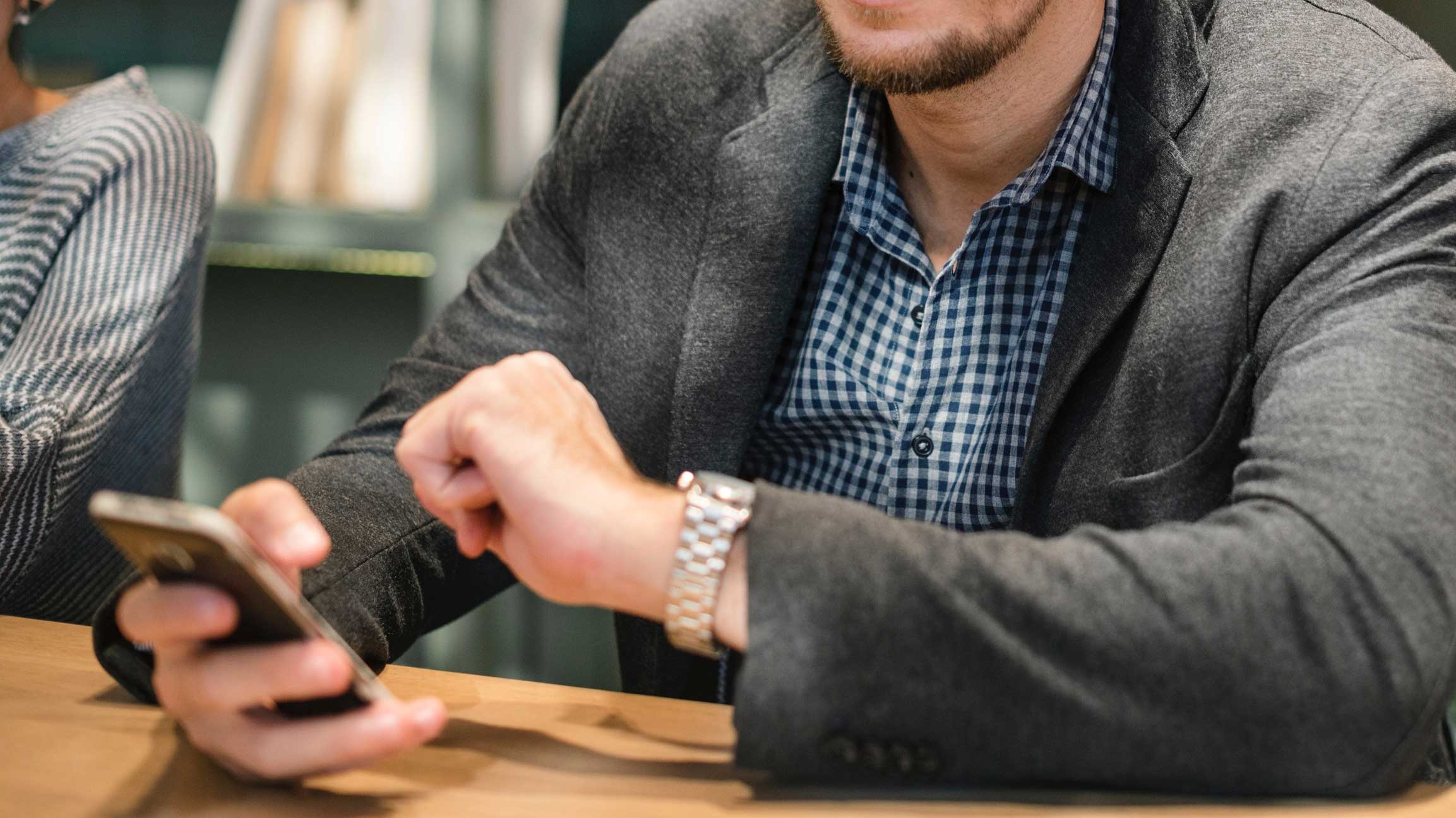 Mãos de um homem segurando um celular.
