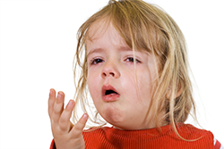 Toddler with red, itchy eyes coughing due to an allergic reaction.