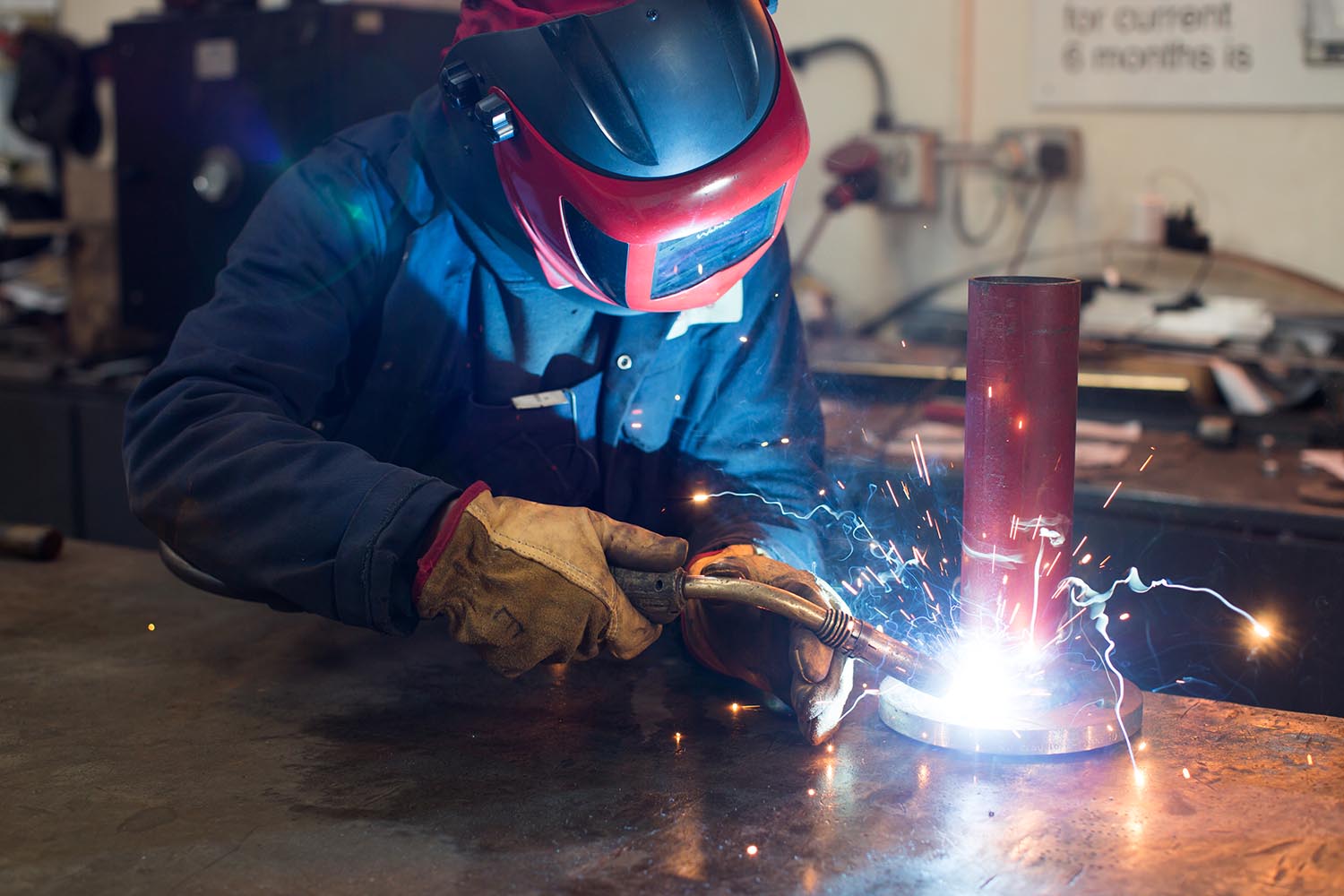 Engineer welding pipework in factory with sparks flying
