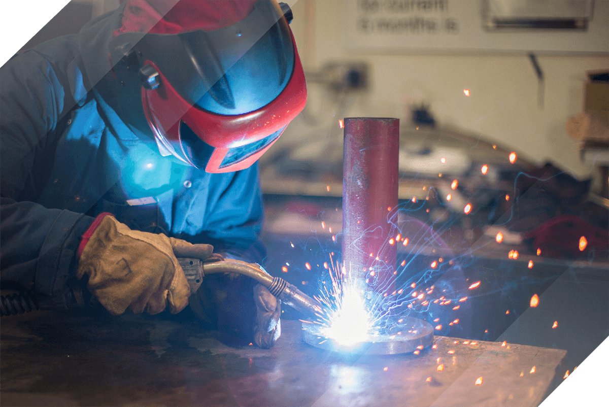 Experienced steel engineer welding some pipework with a blow torch in a South Wales workshop
