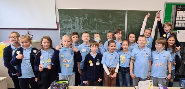 Na zdjęciu grupa uczniów klasy 4 prezentująca znaczki ekspertów tabliczki mnożenia