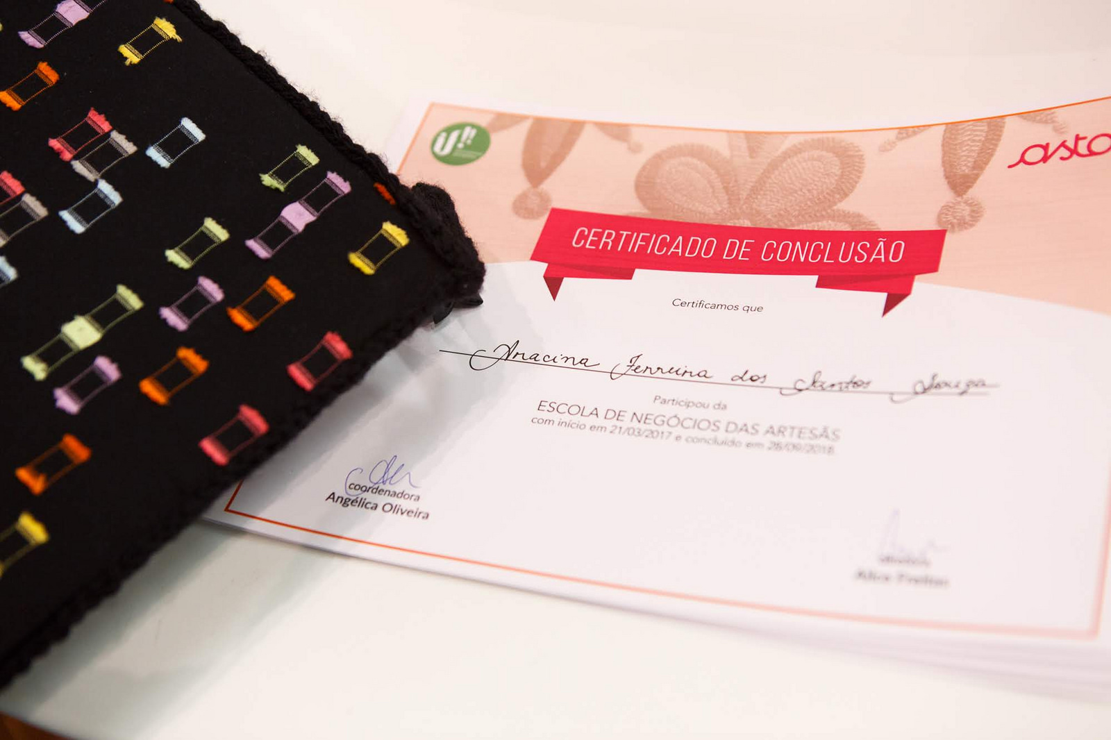 Certificado de conclusão de curso da Escola de Negócio das Artesãs da Rede Asta em parceria com a IF! com capelo ao lado
