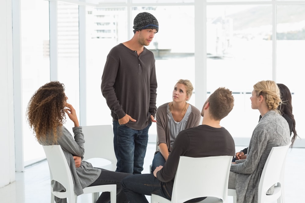 Man with hat talks to support group members