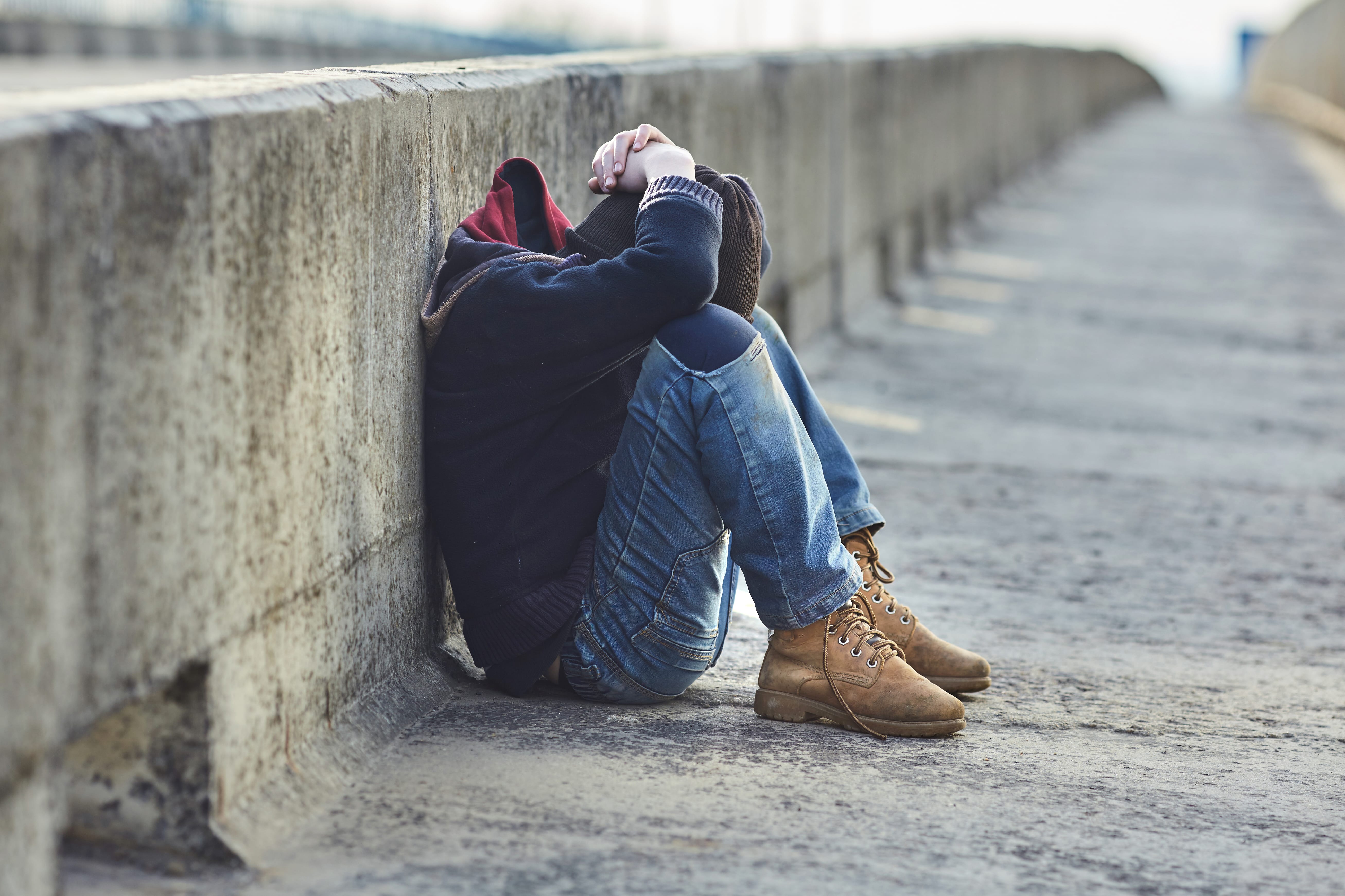 Homeless boy sitting on bridge