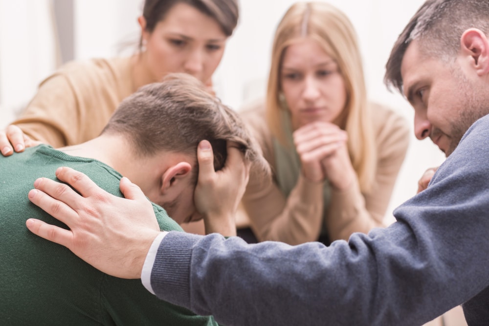 Family consoling a young man