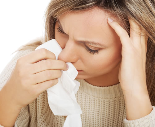 woman suffering from non-allergic rhinitis holding a white tissue to her runny nose