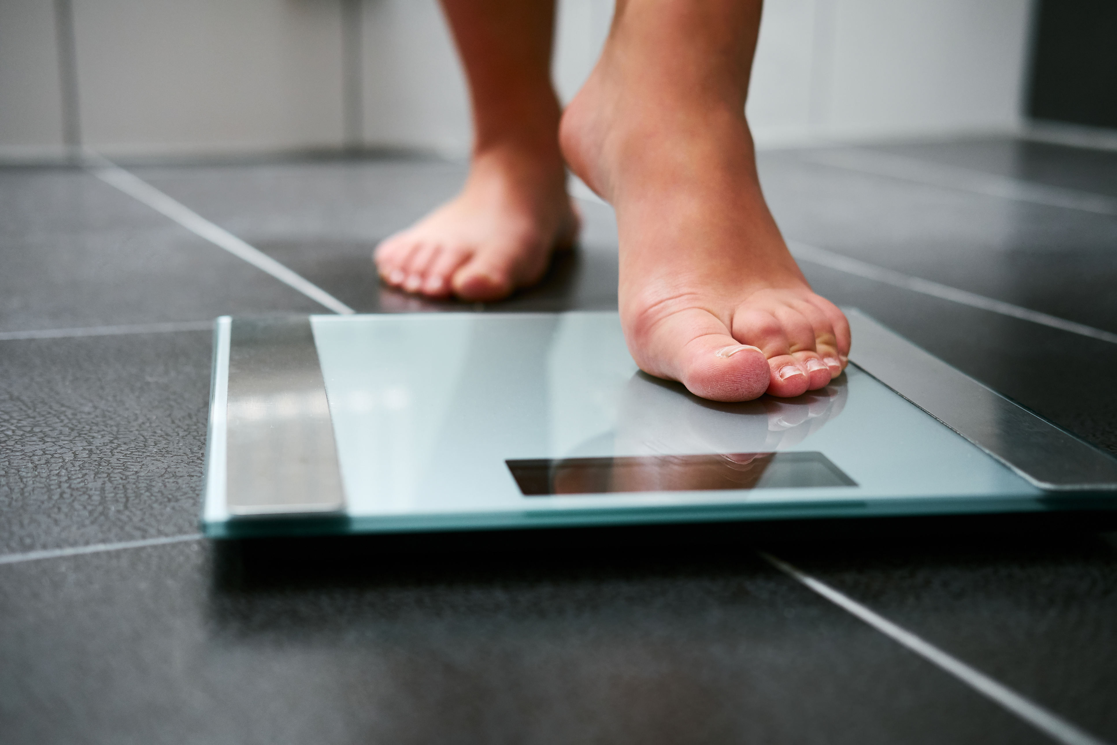 Person stepping onto weight scales BMI