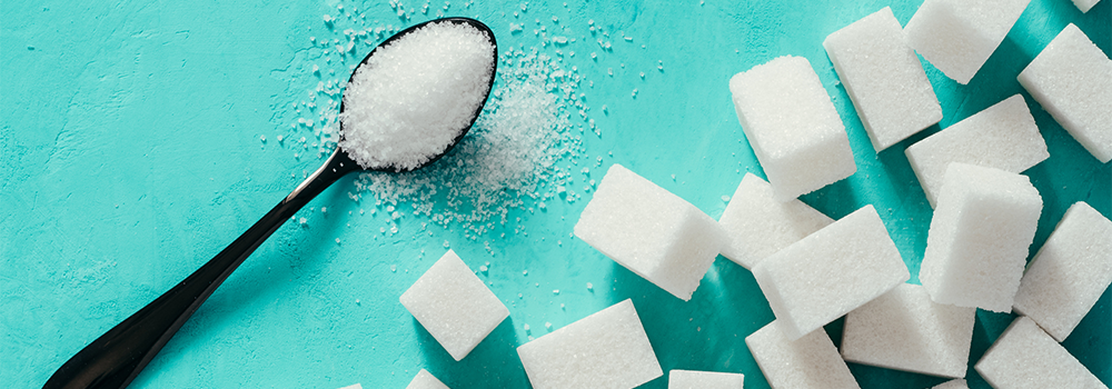 sugar cubes and sugar on a teaspoon blue background
