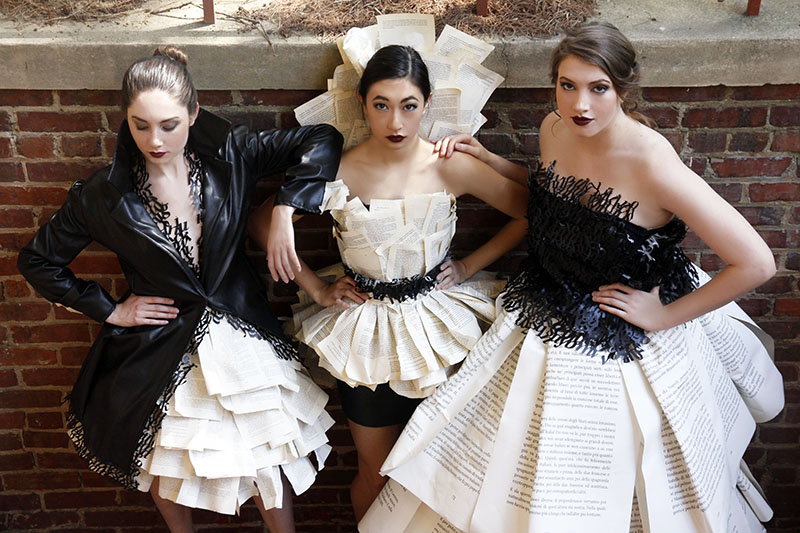Three models in leather typography and book page dresses.