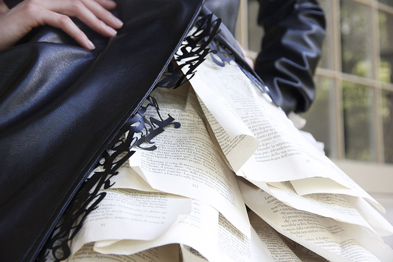 Close up of dress with book page skirt, leather jacket, and leather typography lining.