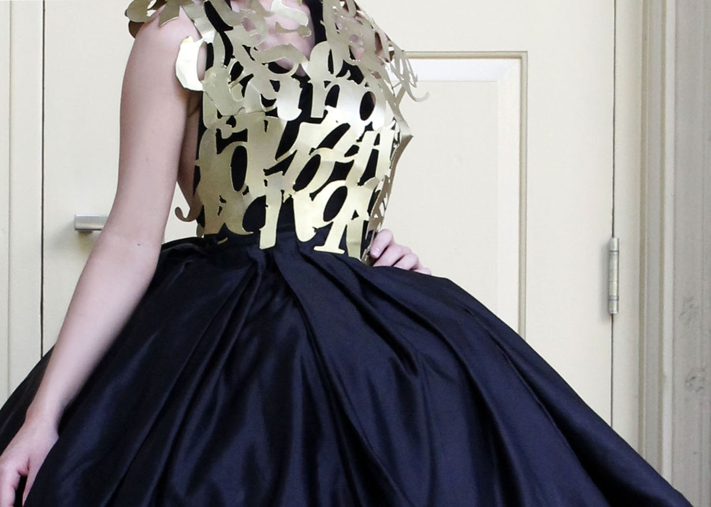 Metal typographic top, like armor, and a wide silk black hoop skirt.