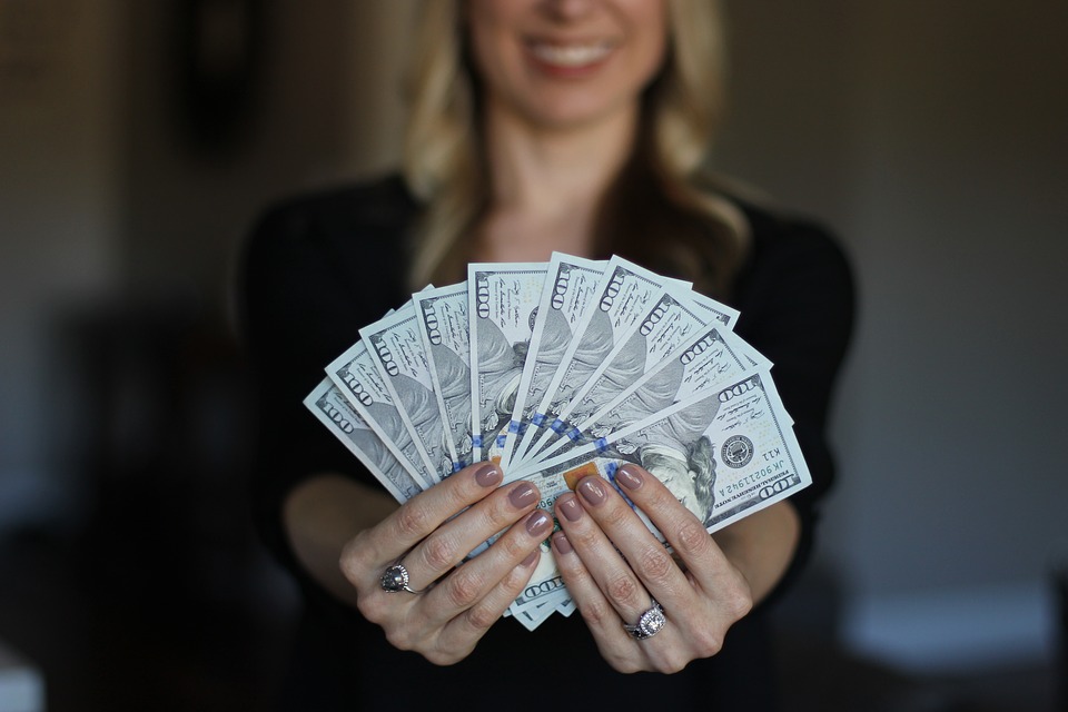 A woman holding a handful of $100 bills