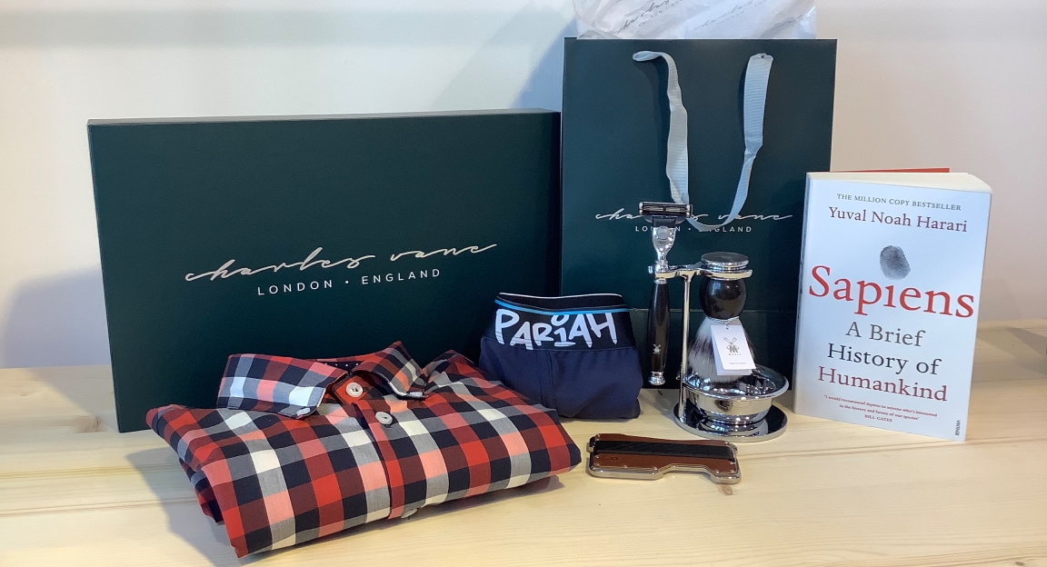 display table with red and black charles vane plaid shirt, navy pariah underwear, shaving set, a book and charles vane packaging.