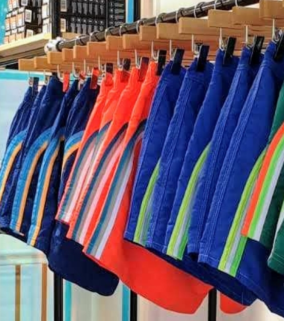 a bunch of colorful retro styled beach shorts hanging on a clothes rack in store.