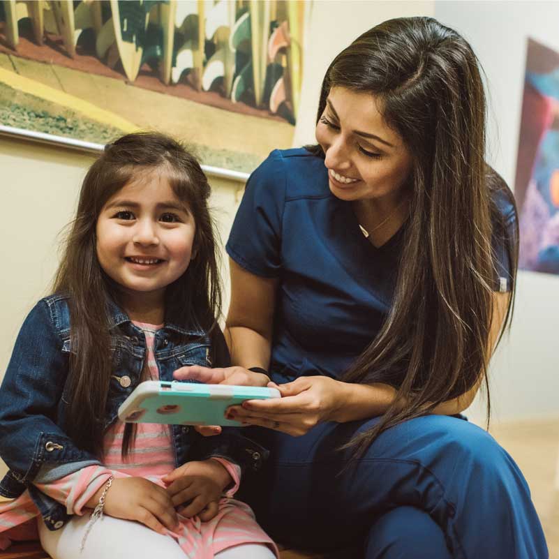About Wildey Pediatric Dentistry In San Antonio Tx Photo Of A Female Team Member With Young Patient Looking At Phone