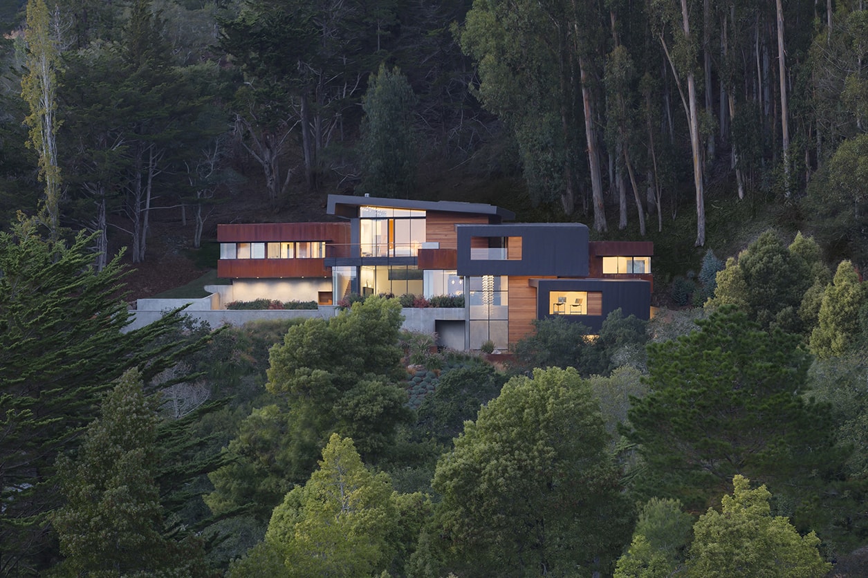 Designed for a tech entrepreneur couple and their young twins, the home in Mill Valley, California is a modern composition in articulated form. Located on a large wooded canyon site and sharing the land with a family of nesting red-tail hawks, this residence is designed to integrate into the landscape through cascading forms and natural materials. The exterior is a montage of natural wood, oxidized steel, and rich zinc panels blending with the surrounding foliage with many of these materials utilized on the interiors as well blurring the lines between inside and out. The main feature of the house is an observatory for the nesting raptors in the tree above visible through the upper level roofs to connect the interior to the beautiful natural surroundings.