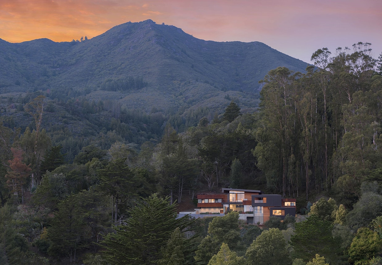 Designed for a tech entrepreneur couple and their young twins, the home in Mill Valley, California is a modern composition in articulated form. Located on a large wooded canyon site and sharing the land with a family of nesting red-tail hawks, this residence is designed to integrate into the landscape through cascading forms and natural materials. The exterior is a montage of natural wood, oxidized steel, and rich zinc panels blending with the surrounding foliage with many of these materials utilized on the interiors as well blurring the lines between inside and out. The main feature of the house is an observatory for the nesting raptors in the tree above visible through the upper level roofs to connect the interior to the beautiful natural surroundings.