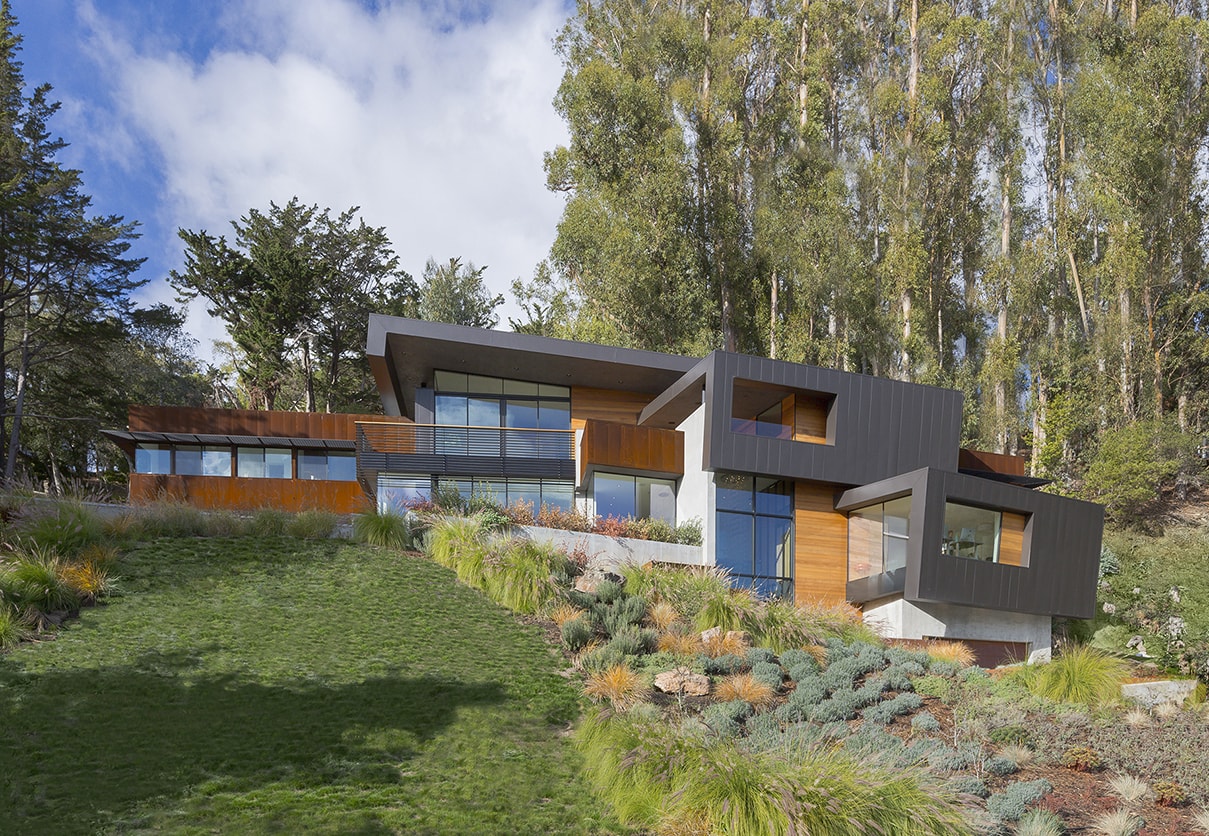 Designed for a tech entrepreneur couple and their young twins, the home in Mill Valley, California is a modern composition in articulated form. Located on a large wooded canyon site and sharing the land with a family of nesting red-tail hawks, this residence is designed to integrate into the landscape through cascading forms and natural materials. The exterior is a montage of natural wood, oxidized steel, and rich zinc panels blending with the surrounding foliage with many of these materials utilized on the interiors as well blurring the lines between inside and out. The main feature of the house is an observatory for the nesting raptors in the tree above visible through the upper level roofs to connect the interior to the beautiful natural surroundings.