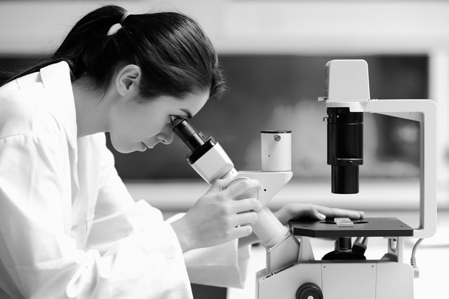 woman looking through microscope