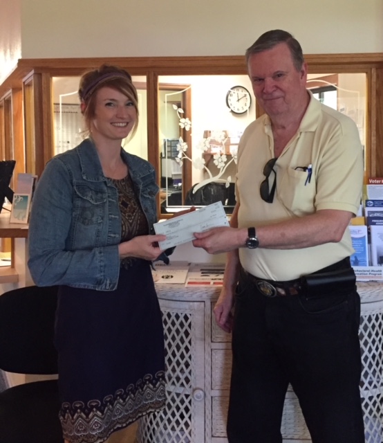 A man and a woman holding a donation check.