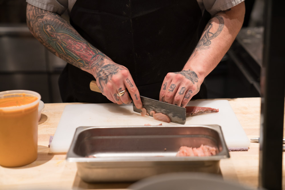 A chef slices pork at Canon in East Sacramento for Visit Sacramento.