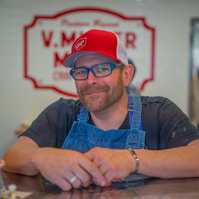 Eric V. Miller of V. Miller Meats smiles behind the counter of his butcher shop in East Sacramento for Visit Sacramento.