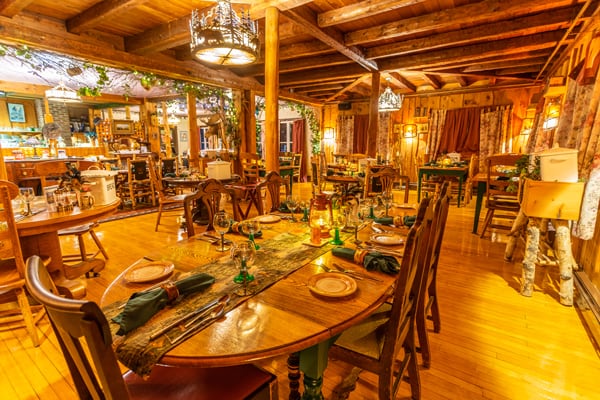 A wide view of the 1886 Stagecoach Dining Room decorated with original Adirondack decor, hand-painted glasses, and Speakeasy accents.