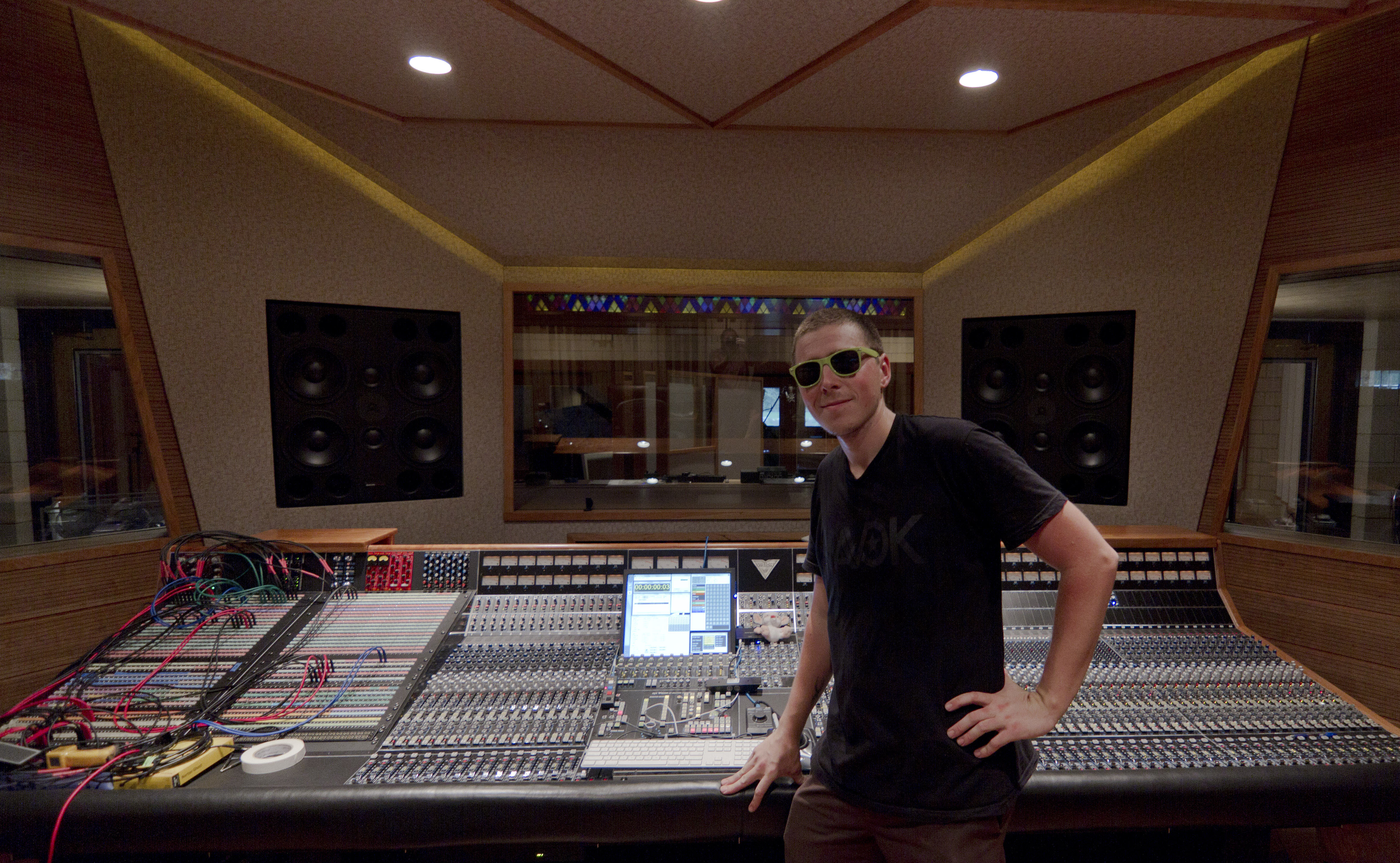Portrait at a sound studio in front of a massive sound mixing board.